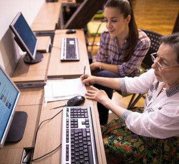 A volunteer teaches a homeless woman how to use a computer in the library. A volunteer teaches a homeless woman how to use a computer in the library.
