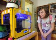 in photo litttle girl looking at 3D printer