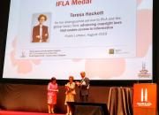 Teresa Hacket receives the award at the IFLA congress. Backdrop is of a banner of Teresa.