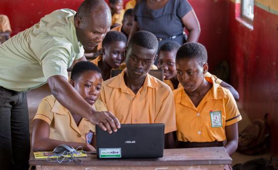 Teacher George Ebo Brown showing children at Archbishop Amissah Junior High School in Western Region how to use a laptop computer. Photo by Ryan Yingling.