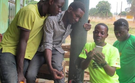 A group of young people looking at the screen of a smartphone. 