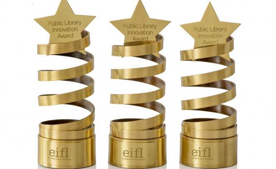 Three innovation award trophies - a golden spiral design, with a star on top.